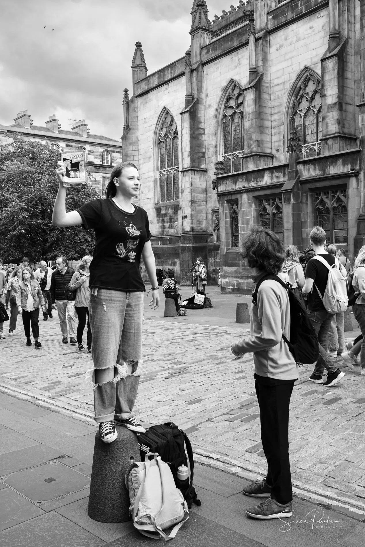 A woman holding a flyer as people pass on an Edinburgh street during the Fringe
